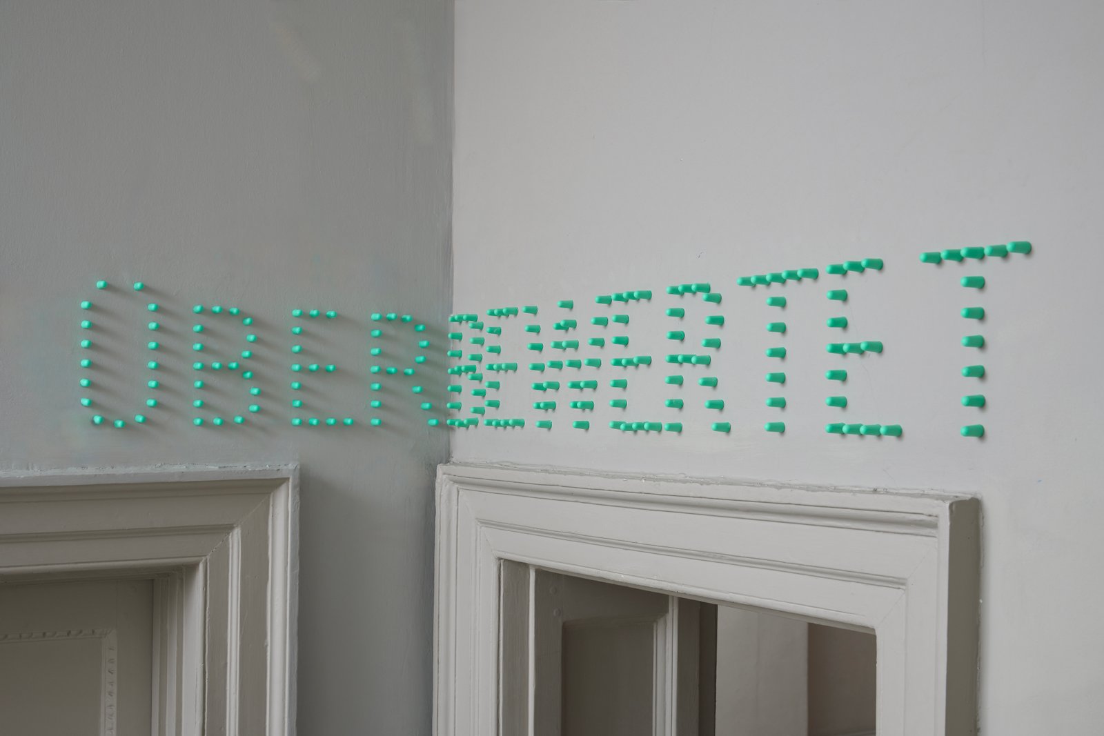 Dermot O'Brien 'Überbewertet' green foam ear plugs, 2025, 24(h)x196cm, photography by Andy Keate Dermot O'Brien 'Überbewertet' green foam ear plugs, 2025, 24(h)x196cm, photography by Andy Keate