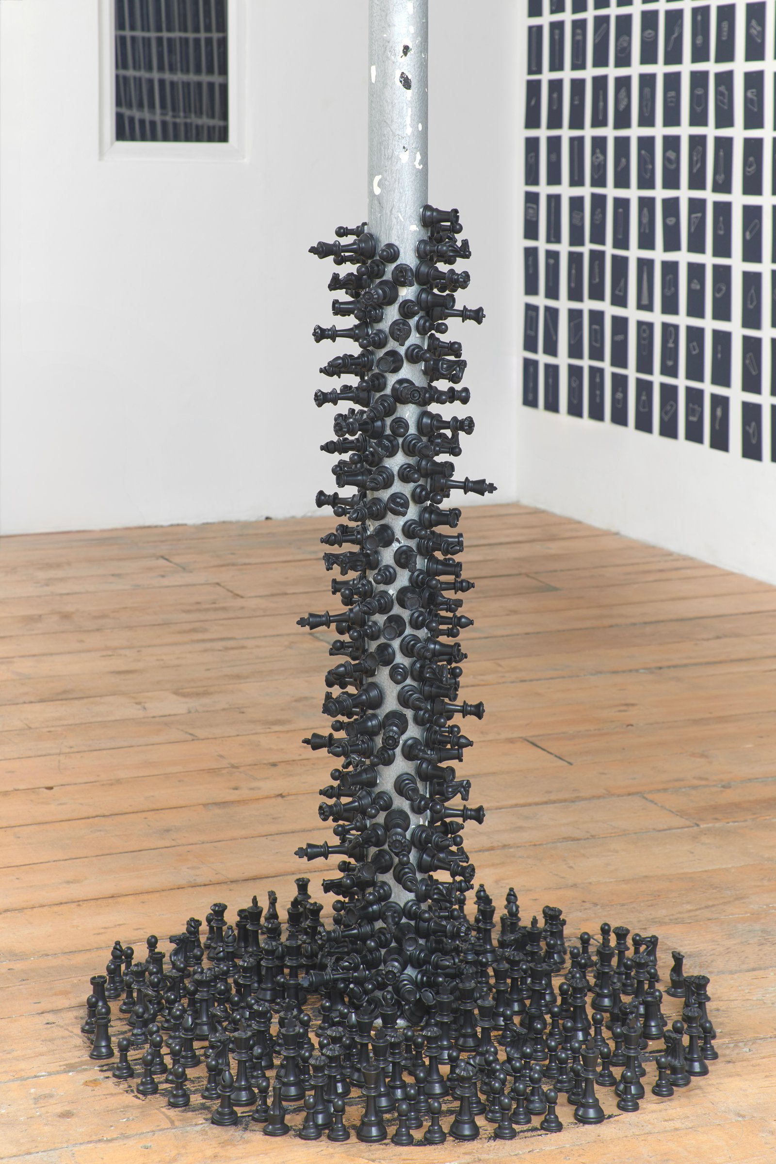 Dermot O'Brien 'Absolute Pin' 350 (approx) black polymer chess pieces, adhesive, 120(h)x70x70cm diameter (approx) 2025 (installed on and around central metal support) photography by Andy Keate at Tension Fine Art Dermot O'Brien 'Absolute Pin' 350 (approx) black polymer chess pieces, adhesive, 120(h)x70x70cm diameter (approx) 2025 (installed on and around central metal support) photography by Andy Keate at Tension Fine Art