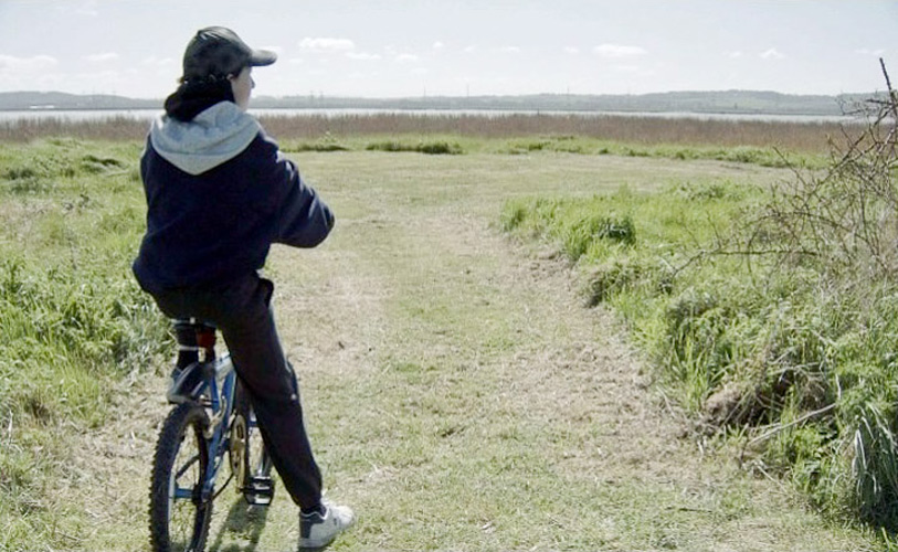 Lynn MacRitchie: The Towers of Ilium, 2013, Reilly Tripp as the Boy on a Bike looking at fight/burn site