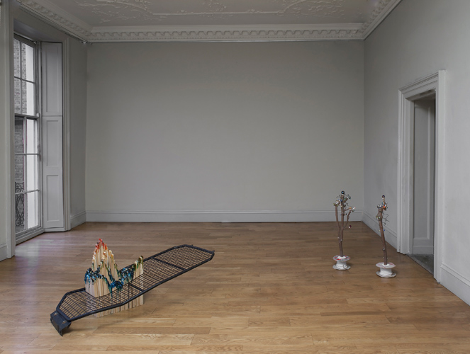 Domain, an exhibition by Mhairi Vari, installation view showing 'Shift' (mdf, dylon, van security grille, 70(h)×160×80cm 2011) on left and 'Retired Skitter Links' (a pair of Sycamore branches, link fencing wire, pin–heads, marbles, cable and reel, hot–melt glue, 90(h)×60×30cm 2011) on right, photo by Andy Keate